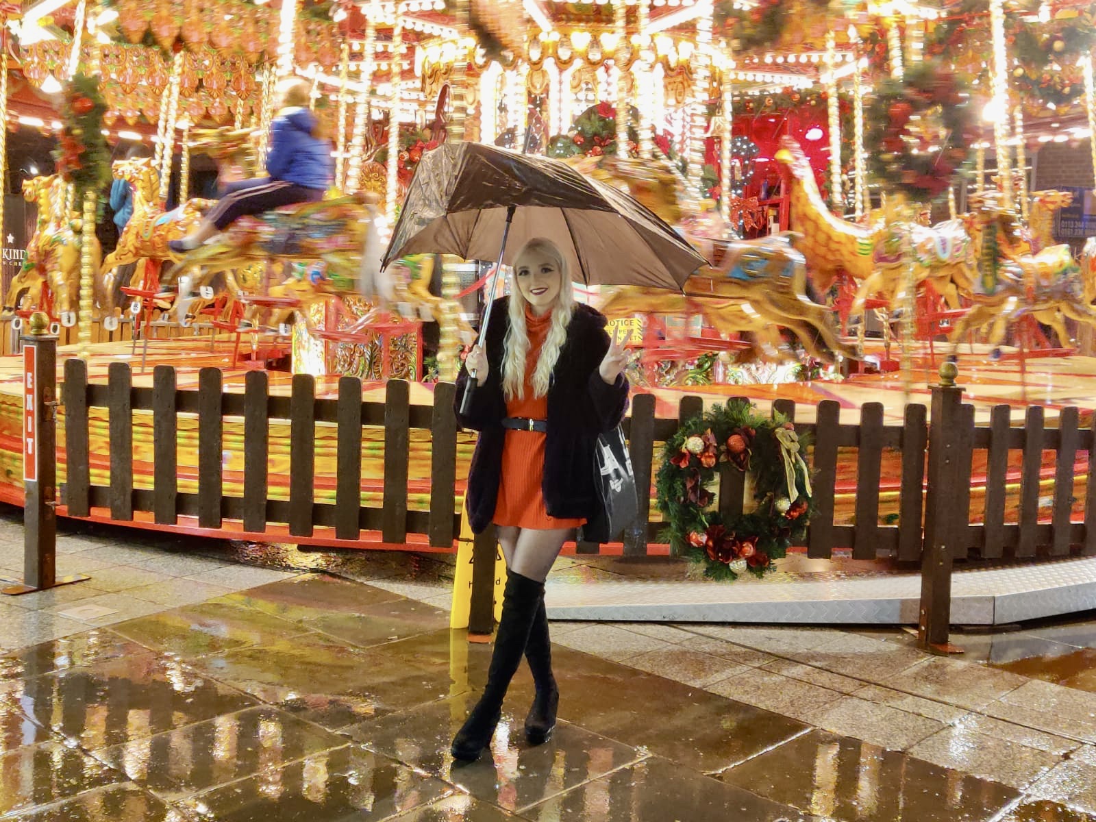 Decorative image of Flossie standing in front of a carousel holding a very broken umbrella